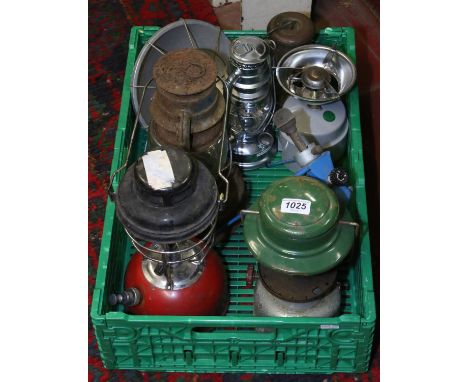 A box of hurricane lamps, camping stoves and a vintage wolf safety lamp.