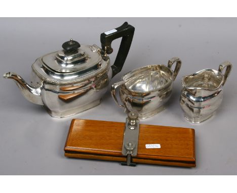 A silver plated three part tea service and a tie press.