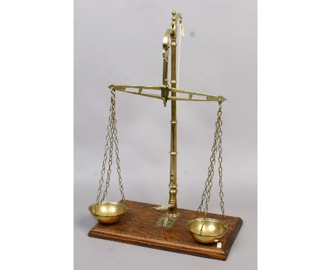 A set of brass scales mounted on an oak plinth marked W & T Avery.