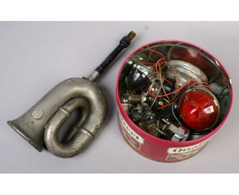 A tin of vintage motorcar lights, dashboard dial and car horn etc.