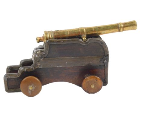 A 19thC small miniature cannon, with brass barrel, the base mahogany with horn button shaped wheels etc., possibly prisoner o