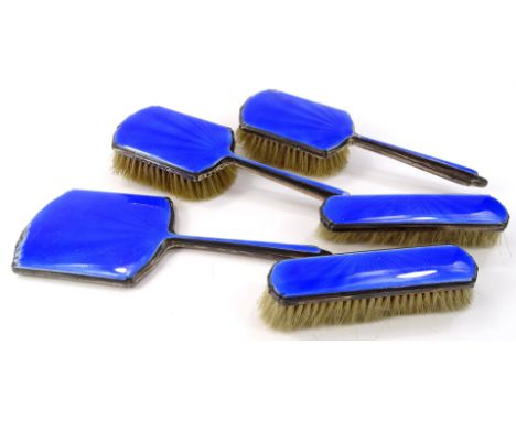 A George V silver and blue enamel five piece dressing table set, comprising hand mirror, 26cm wide, two hair brushes and two 