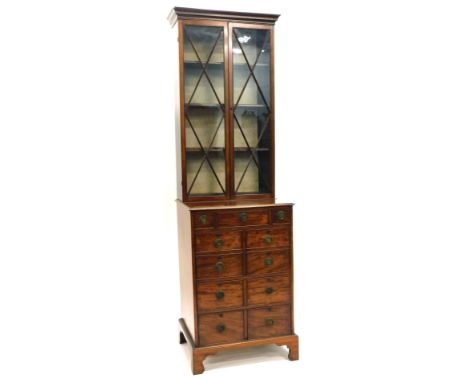 A mahogany bookcase, the top with two doors with geometrical astragals, the base with an arrangement of small drawers, longer