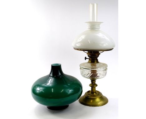 An early 20thC brass and clear glass oil lamp, with shaped reservoir, turned stem, milk glass shade and plain glass chimney, 