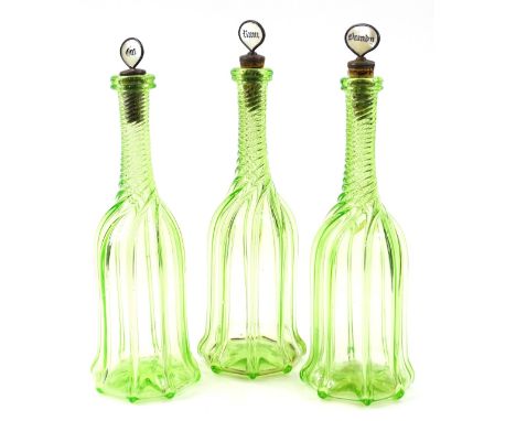 A set of three late Victorian green and clear glass twist decanters, each with mother of pearl stoppers for Rum, Brandy and G