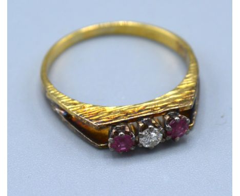 An 18ct Yellow Gold Ruby And Diamond Ring set with central diamond flanked by two rubies within a pierced setting 2.7 gms. ri