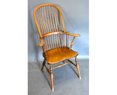 A 19th Century Elm Windsor Armchair with a stick back above a panel seat raised upon turned legs with stretchers 