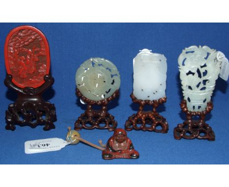 A carved jade plaque, 5.5 x 3.5 cm, on a hardwood stand, two others similar, on stands, a cinnabar lacquer plaque, 7.5 x 5 cm