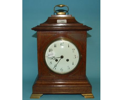 A mantel clock, the enamel dial with Arabic numerals, in an oak case, with brass inlay, 35.5 cm high (over handle) Condition 