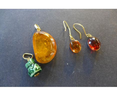 A polished amber pendant, measuring 30mm x 20mm x 9mm with yellow metal mount and pair of similar earrings, size 12mm x 10mm 