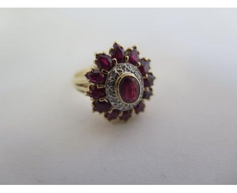 A pretty ruby and diamond ring in 14ct yellow gold, set with a central ruby of 5mm x 4mm approx, surrounded by twelve round c