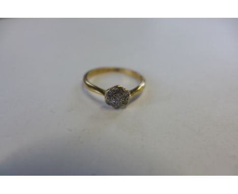 An 18ct gold and platinum diamond set daisy ring, set with seven small round cut diamonds, in a platinum setting, ring size L