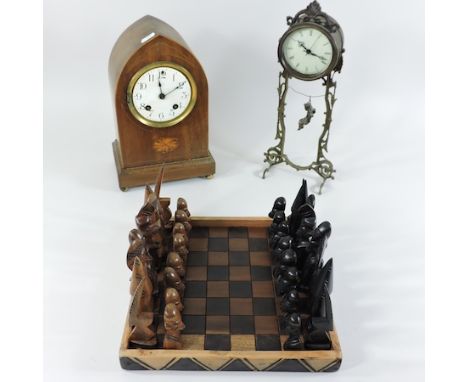 An Edwardian walnut and inlaid mantel clock, 29cm tall, together with a metal mantel clock and an African carved chess set 