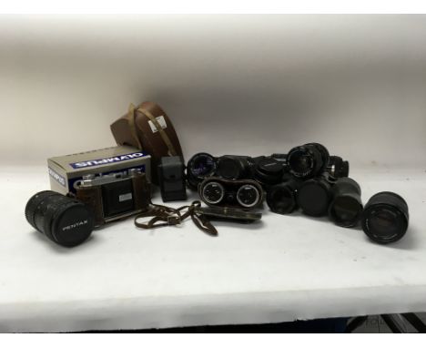 A box off camera parts and accessories with pairs of binoculars and other odd pieces