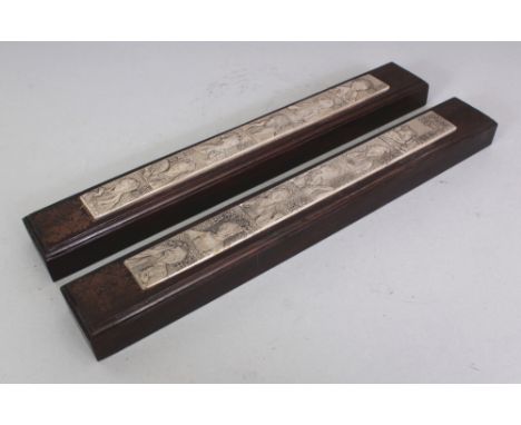 A PAIR OF CHINESE SILVER-METAL & WOOD SCROLL WEIGHTS, of elongated rectangular form, the metal cast with calligraphy and port