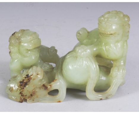 A CHINESE CELADON JADE GROUP, modelled in the form of three Buddhistic lions playing with a ribboned ball, the stone with som