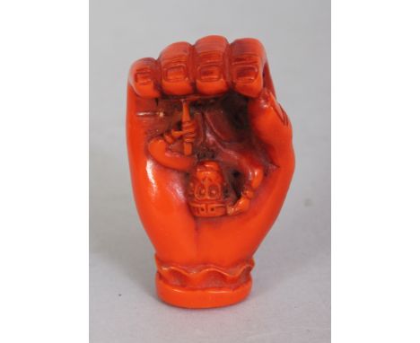 AN UNUSUAL SIGNED JAPANESE CORAL-STYLE NETSUKE, modelled in the form of a hand clasping the Monkey God, 1.75in high.