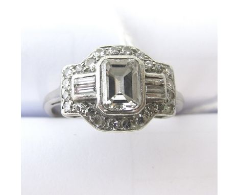 An Art Deco white metal diamond cluster ring set with a central emerald cut diamond, four small emerald cut diamonds surround