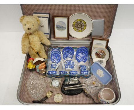 A case of assorted items including a vintage Teddy bear, Poole pottery vase, blue and white willow pattern children's tea set