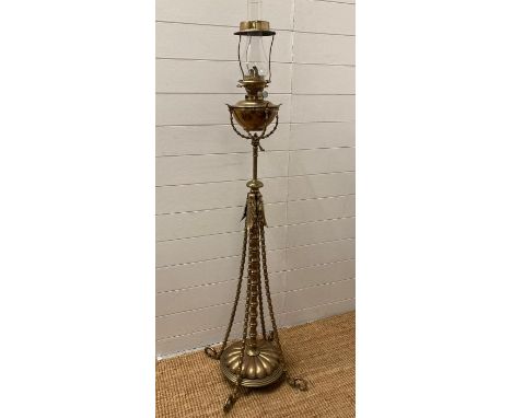 A Victorian brass floor standing oil lamp on four legs with foliate details 