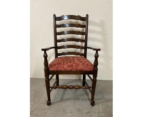 An oak spool turned ladder back arm chair upholstered in red 