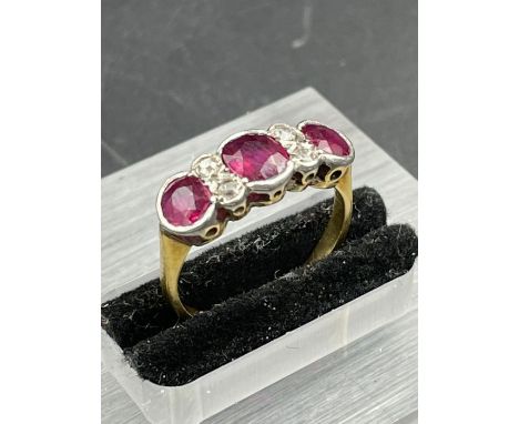 An Antique three stone ruby ring with four small diamonds. Size K