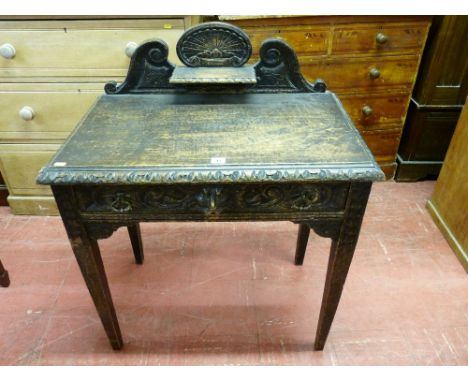 A JACOBEAN STYLE CARVED OAK SIDE TABLE with shaped railback and shelf on a rectangular top with carved moulding, the single f