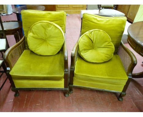 A PAIR OF EARLY 20th CENTURY BERGERE ARMCHAIRS, the walnut frames with cane backs and sides, loose cushion upholstery, on Que