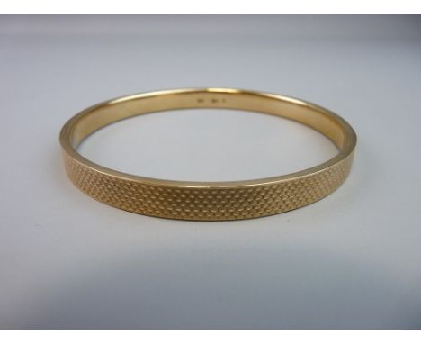 A NINE CARAT GOLD BANGLE  with engine turned decoration, 13.5 grms