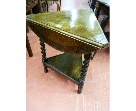 A TRIANGULAR OAK TWO TIER OCCASIONAL TABLE, the three top flaps opening to form a 57 cms diameter circular top on carved bloc