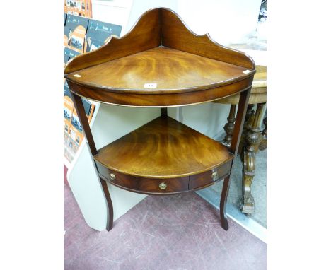 A REPRODUCTION MAHOGANY CORNER STAND with shaped gallery top and bow front shelf, the under tier with central drawer and flan