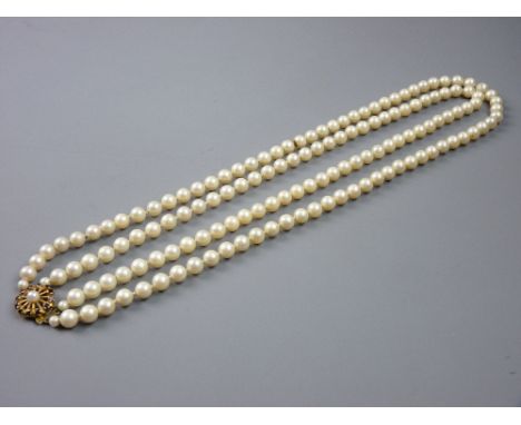 A DOUBLE NECKLACE OF CULTURED PEARLS with fine ruby and pearl decorated circular nine carat gold clasp, 87 grms gross total