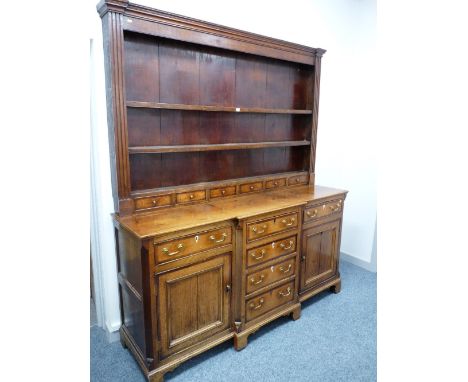 AN EARLY 19th CENTURY NORTH WALES OAK & CROSSBANDED MAHOGANY BREAKFRONT DRESSER, the three shelf wide boarded rack with mould