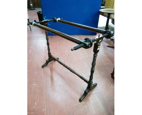 AN EARLY VICTORIAN TAPESTRY STRETCHER with hinged cylinder bearers, twist supports, turned wooden screw tighteners on carved 