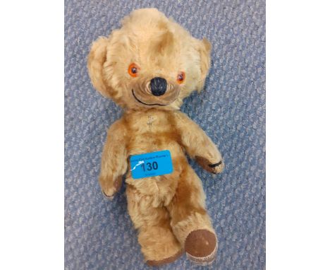 A vintage Merrythought teddy bear with glass bead eyes and a label to the foot, 23cm high.Condition: requires attention, see 