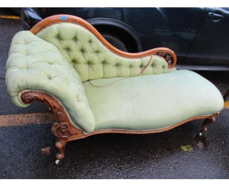 A Victorian walnut chaise longue having a carved, pierced frame, button back upholstery and short cabriole feet 