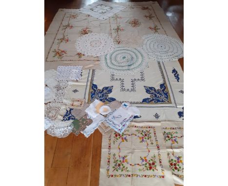 A large mid 20th Century cream cotton tablecloth with hand embroidered sections of blue and gold sea serpents surrounding a c