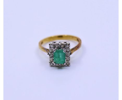 An 18ct emerald and diamond cluster ring, claw set emerald-cut emerald and fourteen eight-cut diamonds