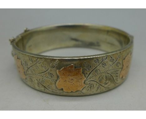 A silver bangle with gold decoration