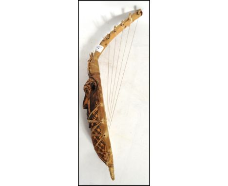 A vintage 20th century African tribal 5 string harp of wooden and animal hide construction with carved tribal mask to front. 