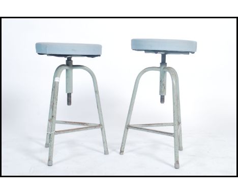 A pair of vintage mid century retro industrial medical / machinists stool raised on tripod legs with adjustable swivel seats 