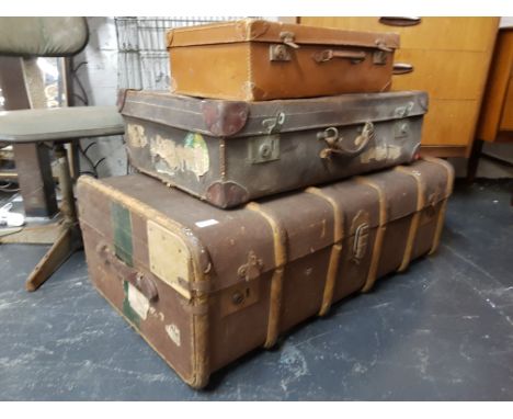 A stack of vintage early 20th century trunks to include a canvas and wooden bound steamer trunk and 2 leather 