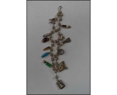 A silver charm bracelet having fret pieced ball spacers with bolt ring clasp, charms to include dog, miniature pen knives,hal