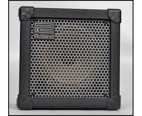 A vintage Roland Cube 15 black guitar amp having a metal grille front.