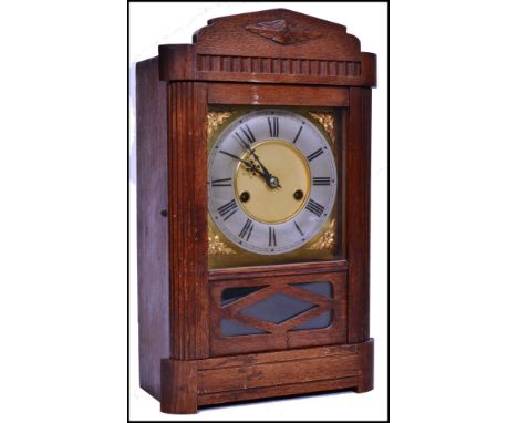 An oak eight-day pendulum mantel clock having a 2 train movement with a gilt brass face and numerical dial.