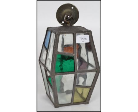 An early 20th century Arts & Crafts hexagonal glass and brass porch lantern, the stained glass panels in various colours