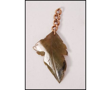 A 9ct gold and jade leaf pendant. The carved green jade in the form of a leaf being set to a 9ct chain. Total weight 10g / Si