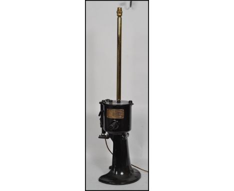 An Industrial heavy ebonised metal dairy machinery seperator being converted to a table lamp. The heavy black machine base wi