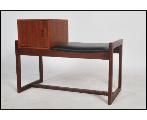 A vintage teak wood telephone table having a telephone book storage area and a black vinyl seat pad raised on quadrille legs.