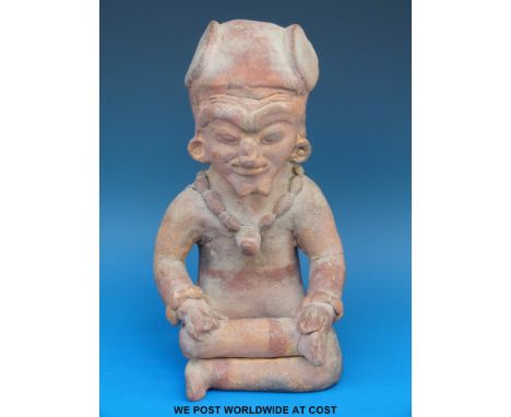 A Mayan terracotta figure in the form of a seated man wearing a necklace, 23cm tall. 